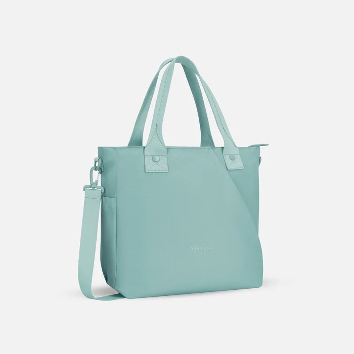 A Sherpani Jetsetter Surf Blue Travel Tote Bag, 3/4 view showing two strap options on white backdrop. #color_surf-blue