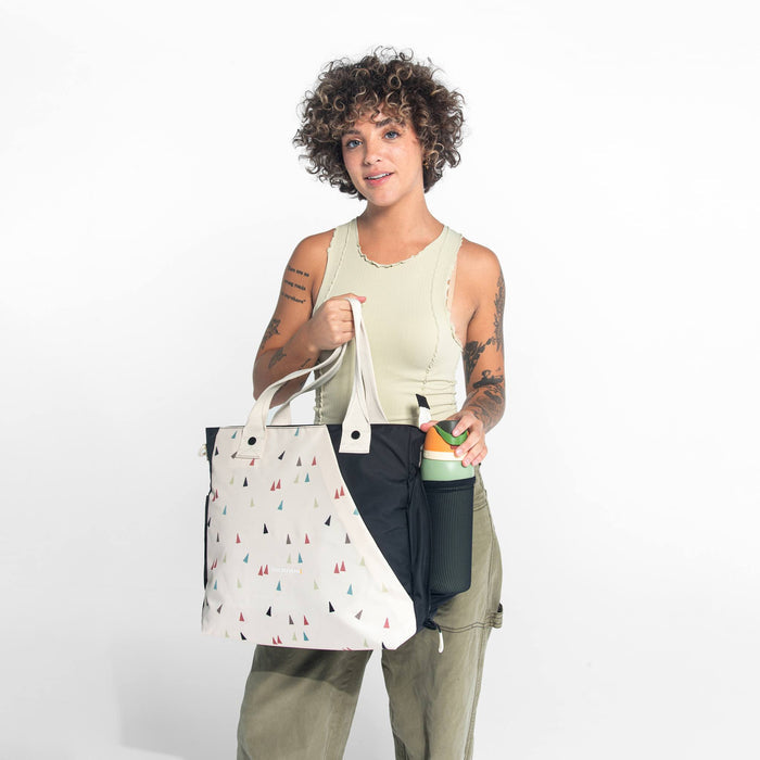 A woman holding a Sherpani Jetsetter Terrazzo Print Travel Tote Bag on white backdrop. #color_terrazzo-print