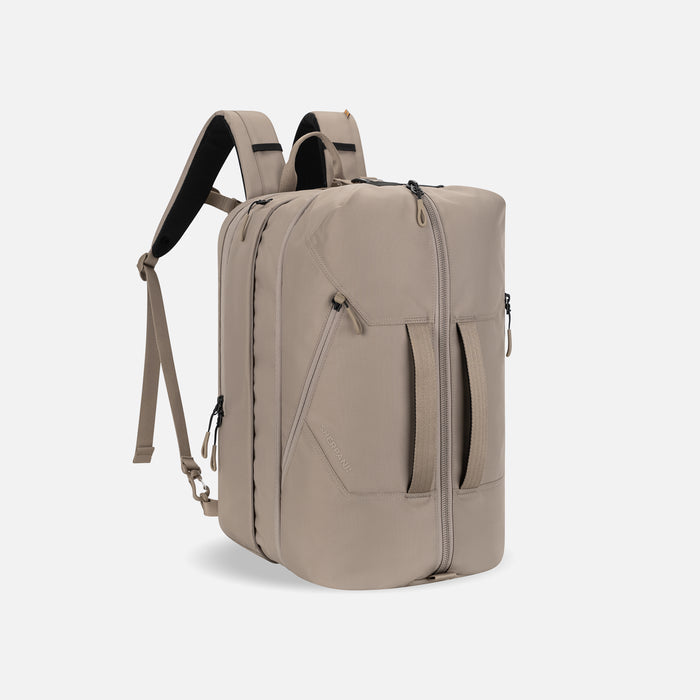 A Sherpani Juno Dune Duffel Backpack, 3/4 view showing duffle straps and main pocket on white backdrop.   #color_dune-tan
