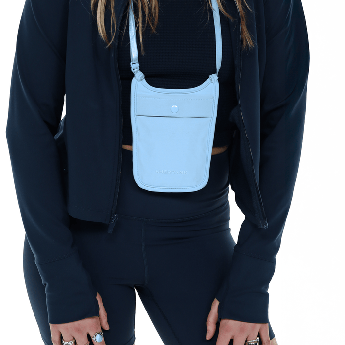 Woman wearing a Sherpani Soft Touch Concealed Neck Wallet Cool Blue around her neck on white background.