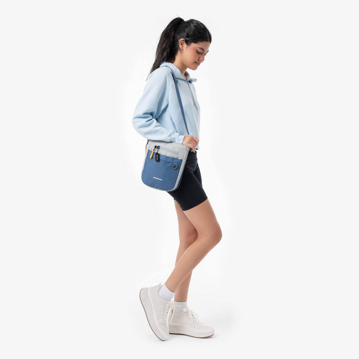Woman wearing a Sherpani Lima Seastone Crossbody Purse against white backdrop.  #color_seastone