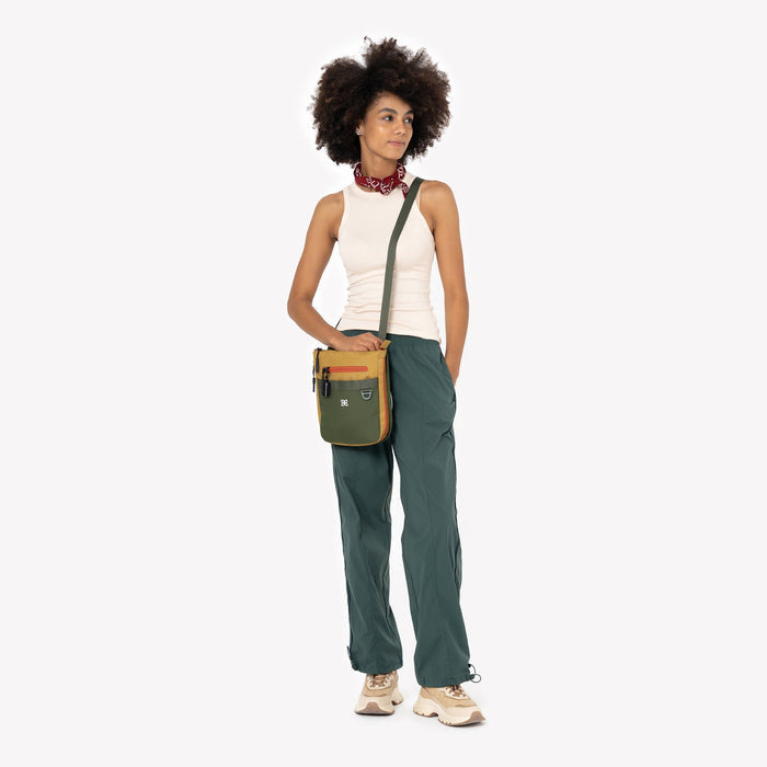 Woman wearing a Sherpani Lima Antelope Crossbody Purse against white backdrop. #color_antelope