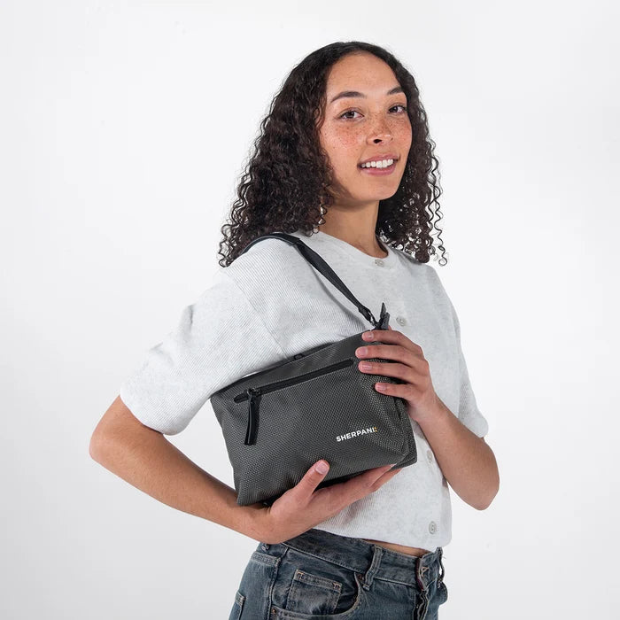 Woman wearing a Sherpani Mei Granite Anti-theft Travel Trio Crossbody against white backdrop.  #color_granite-grey