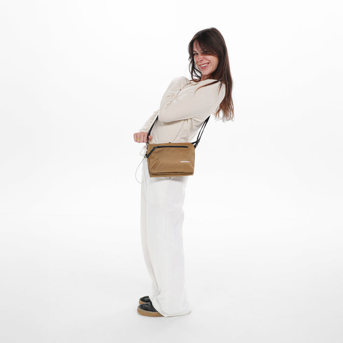 Woman wearing a Sherpani Mei Sand Anti-theft Travel Trio Crossbody against white backdrop.  #color_sand-tan