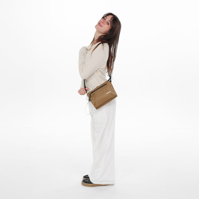 Woman wearing a Sherpani Mei Sand Anti-theft Travel Trio Crossbody against white backdrop.  #color_sand-tan