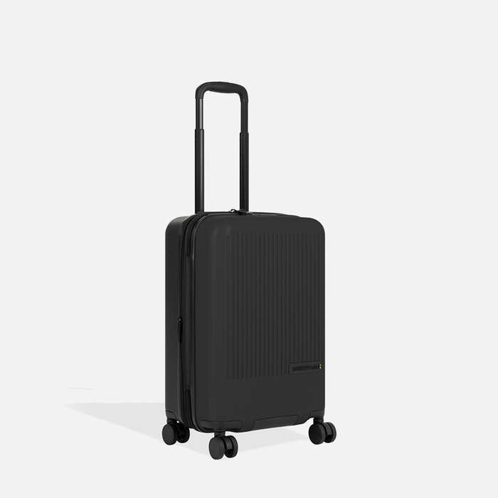 A Sherpani Meridian Black Carry-On Luggage, 3/4 view showing zipper and extender against white background.  #color_black