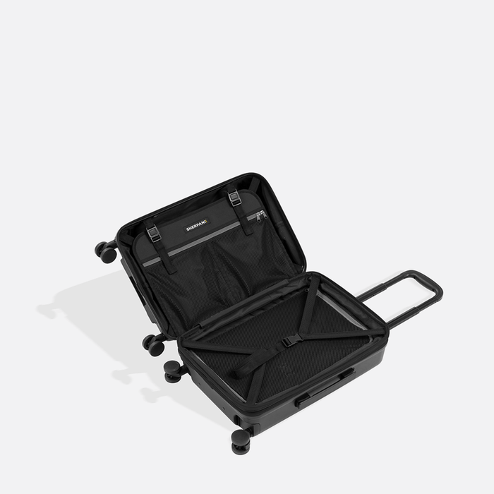 A Sherpani Meridian Black Carry-On Luggage, above view showing inside packing spaces on white backdrop. #color_black