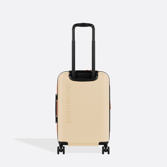 A Sherpani Meridian Chai Beige Carry-On Luggage, back view showing handle and Sherpani logo on white backdrop.  #color_chai-beige
