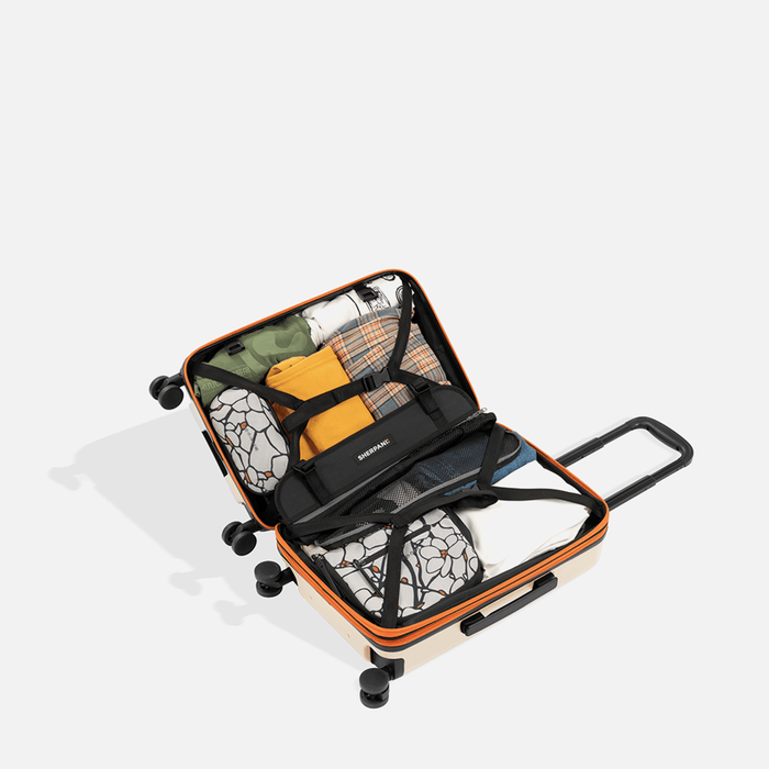 A Sherpani Meridian Chai Beige Carry-On Luggage, above view showing fully packed interior on white backdrop.   #color_chai-beige
