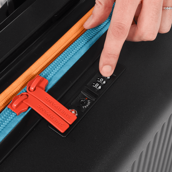 Person setting a code to lock the zippers of a Sherpani Meridian Chromatic Black Carry-On Luggage. #color_chromatic-black