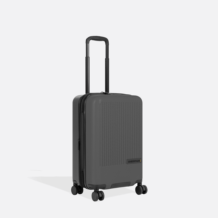 A Sherpani Meridian Granite Carry-On Luggage, 3/4 view showing zipper and extender against white background.  #color_granite-grey