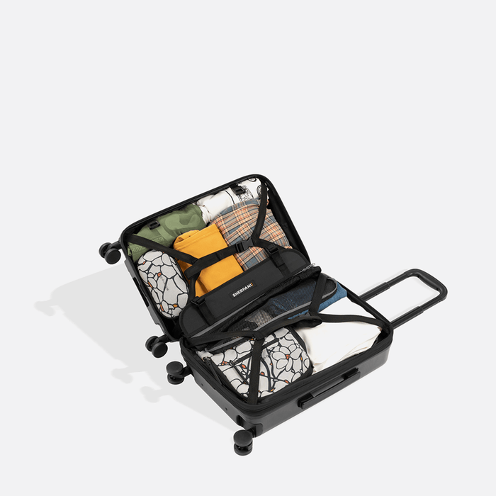 A Sherpani Meridian Granite Carry-On Luggage, above view showing fully packed interior on white backdrop.   #color_granite-grey