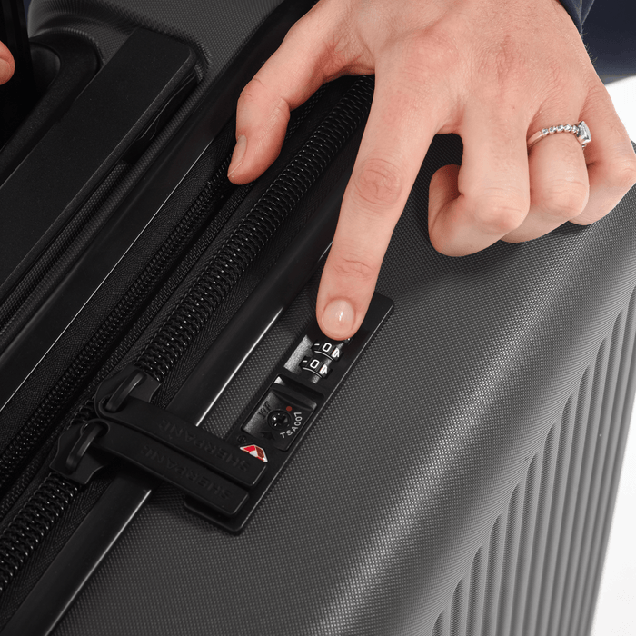 Person setting a code to lock the zippers of a Sherpani Meridian Black Carry-On Luggage. #color_granite-grey