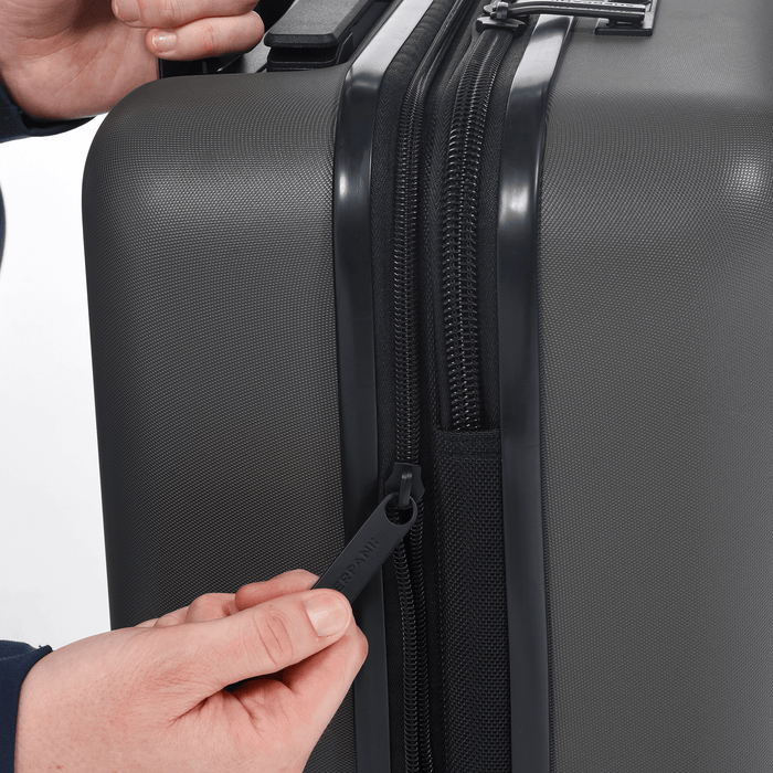 Person zipping up a Sherpani Meridian Granite Carry-On Luggage. #color_granite-grey