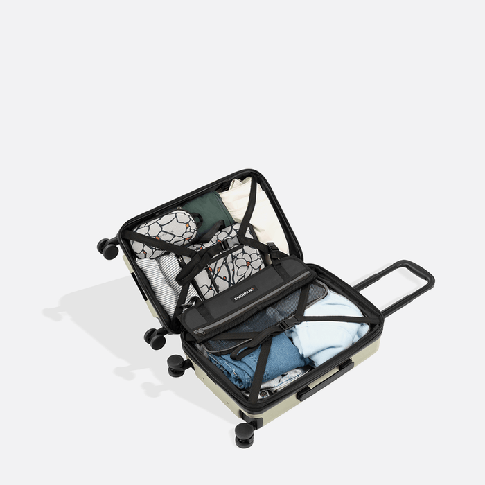 A Sherpani Meridian Matcha Carry-On Luggage, above view showing fully packed interior on white backdrop.  #color_matcha-green