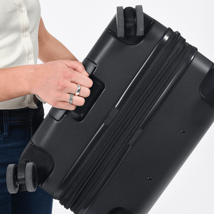 Person holding a Sherpani Meridian Black Checked-Luggage by handle under the wheels. #color_black