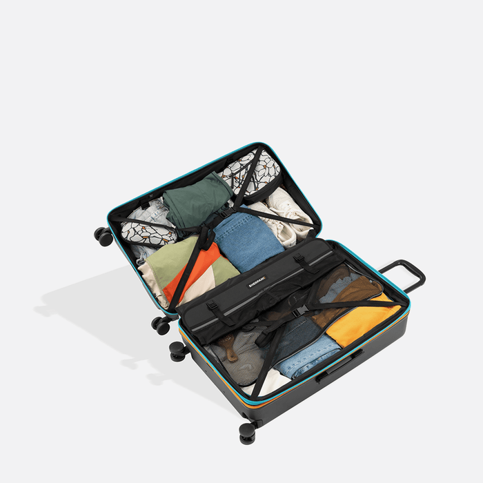 A Sherpani Meridian Chromatic Black Checked-Luggage, above view showing fully packed interior on white backdrop.   #color_chromatic-black