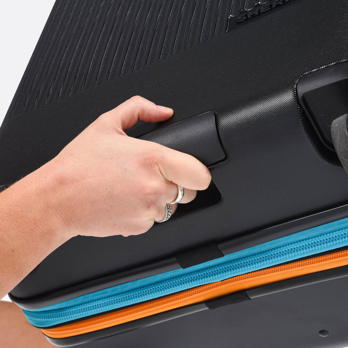 Person holding a Sherpani Meridian Chromatic Black Checked-Luggage by handle under the wheels. #color_chromatic-black