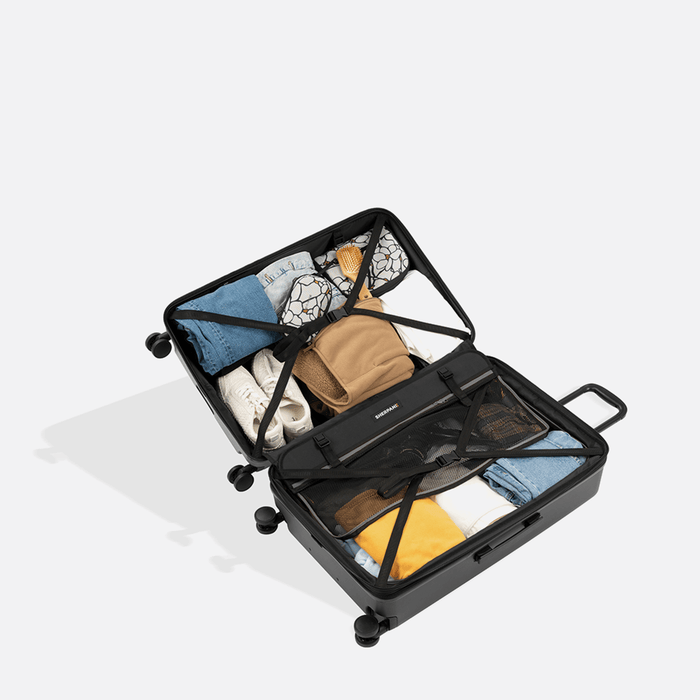 A Sherpani Meridian Granite Carry-On Luggage, above view showing fully packed interior on white backdrop.   #color_granite-grey