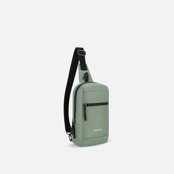 A Sherpani Metro Aloe Mist Green Anti-theft Reversible Sling, 3/4 view showing strap & lockable pocket on white background. #color_aloe-mist-green