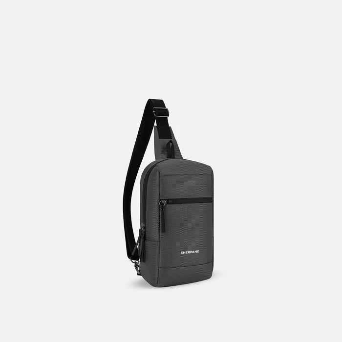 A Sherpani Metro Granite Anti-theft Reversible Sling, 3/4 view showing strap & lockable pocket on white background.  #color_granite-grey