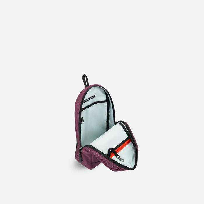 A Sherpani Metro Smoky Orchid Anti-theft Reversible Sling, 3/4 view open showing inside pocket against white background. #color_smoky-orchid-pink