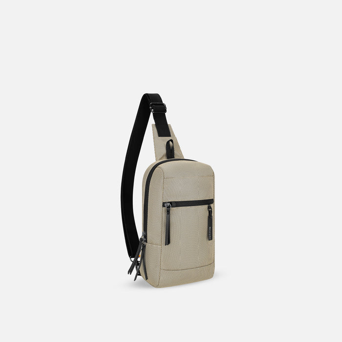 A Sherpani Metro Straw Beige Anti-theft Reversible Sling, 3/4 view showing strap & lockable pockets on white backdrop. #color_straw-signature