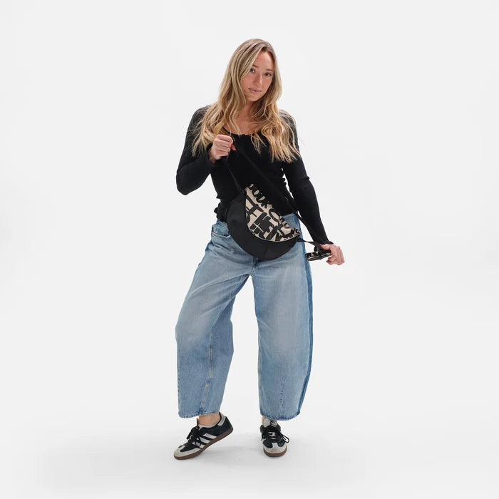 Woman wearing a Sherpani Milli Ciao Print Mini Messenger against white backdrop.  #color_ciao-print
