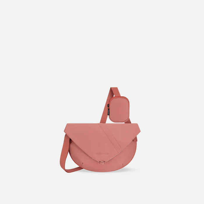 A Sherpani Milli Desert Pink Mini Messenger, front view showing lockable front zipper pocket against white background.  #color_desert-pink
