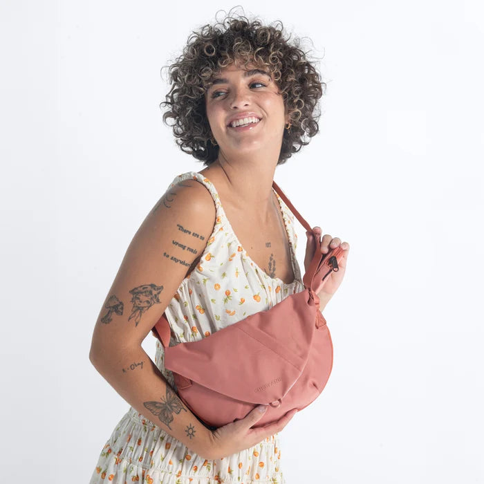 Woman wearing a Sherpani Milli Desert Pink Mini Messenger against white backdrop.  #color_desert-pink
