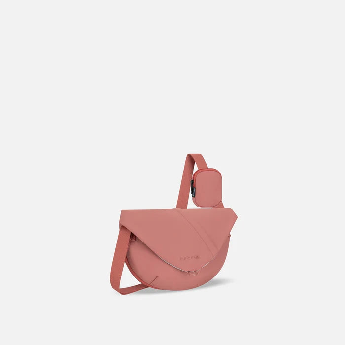 A Sherpani Milli Desert Pink Mini Messenger, 3/4 view showing front flap pocket and strap on white backdrop.  #color_desert-pink