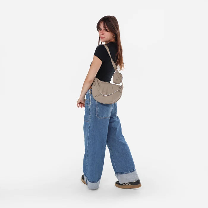 Woman wearing a Sherpani Milli Dune Mini Messenger against white backdrop.  #color_dune-tan