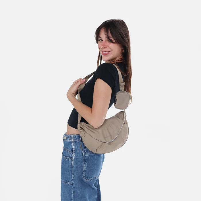 Woman wearing a Sherpani Milli Dune Mini Messenger against white backdrop.  #color_dune-tan