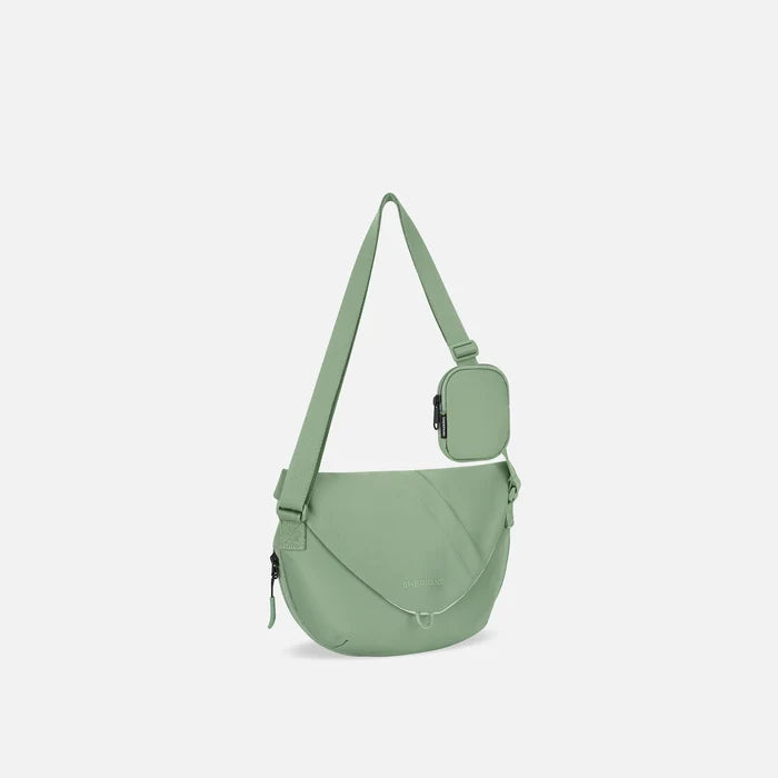 A Sherpani Milli Olivine Mini Messenger, 3/4 view showing front flap pocket and strap on white backdrop.  #color_olivine-green