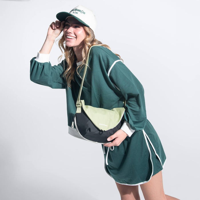 A woman wearing a Sherpani Milli Palm Green Mini Messenger against a white background.  #color_palm-green