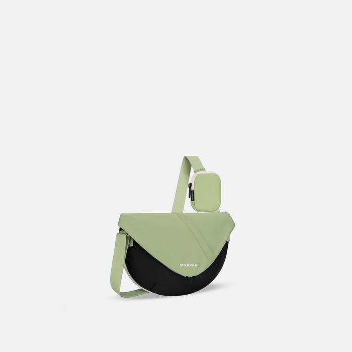 A Sherpani Milli Palm Green Mini Messenger, 3/4 view showing front flap pocket and strap on white backdrop.   #color_palm-green