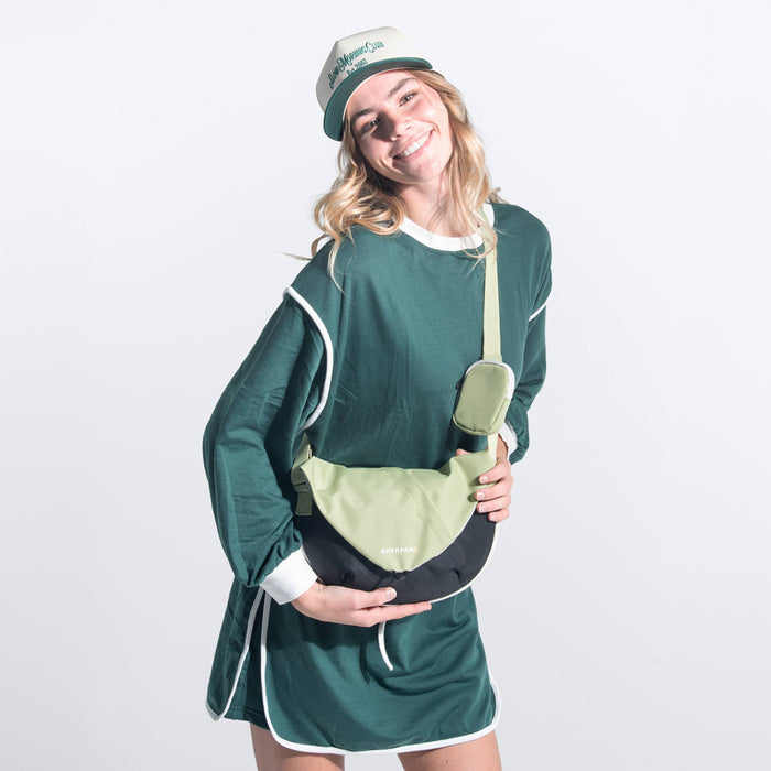 A woman wearing a Sherpani Milli Palm Green Mini Messenger against a white background.  #color_palm-green