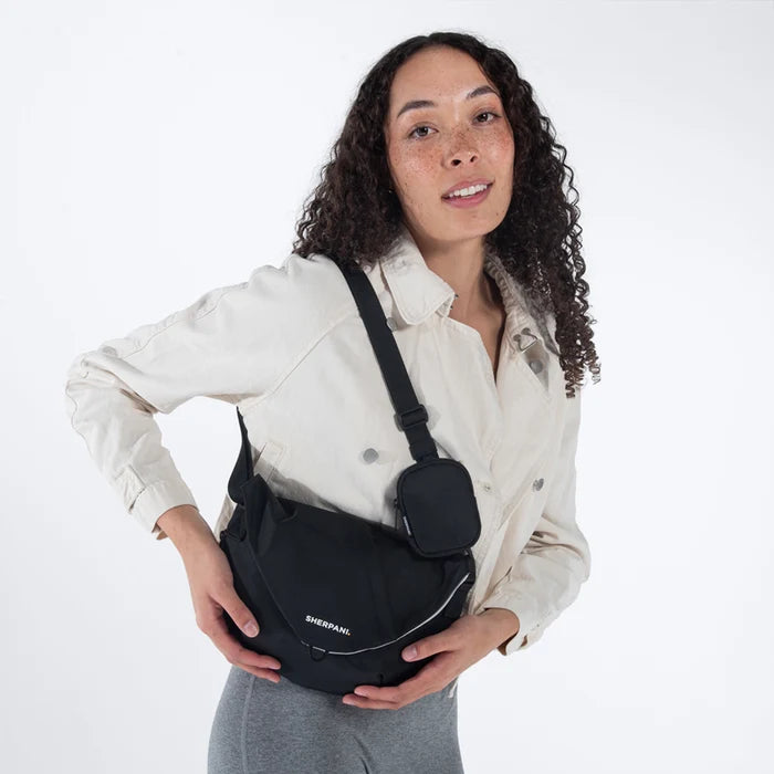 Woman wearing a Sherpani Milli Raven Black Mini Messenger against white backdrop.  #color_raven-black