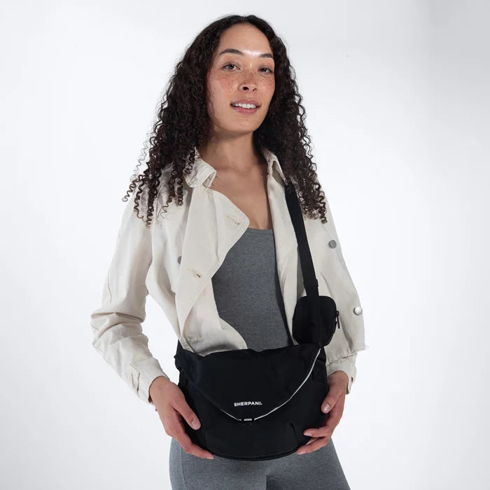 Woman wearing a Sherpani Milli Raven Black Mini Messenger against white backdrop.  #color_raven-black
