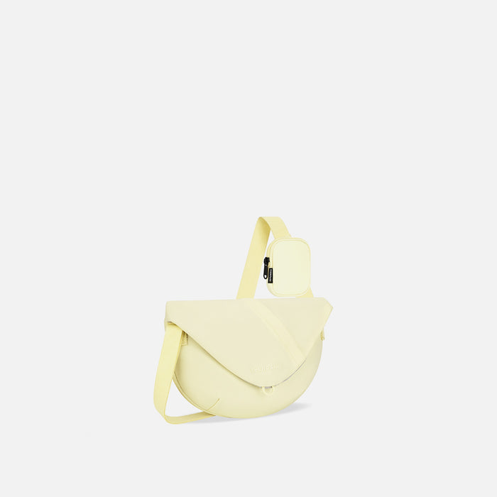 A Sherpani Milli Sol Yellow Mini Messenger, 3/4 view showing front flap pocket and strap on white backdrop.   #color_sol-yellow