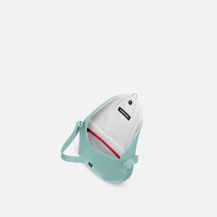 A Sherpani Milli Surf Blue Mini Messenger, above view showing inside main pocket against white backdrop.    #color_surf-blue