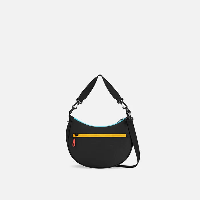 A Sherpani Mina Chromatic Black Medium Crossbody Bag, back view showing straps and lockable pocket on white background.  #color_chromatic-black