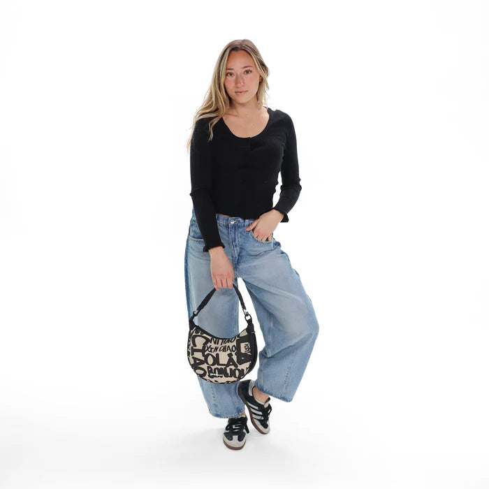 A woman holding a Sherpani Mina Ciao Medium Crossbody Bag in her hands with short-strap attachment. #color_ciao-print