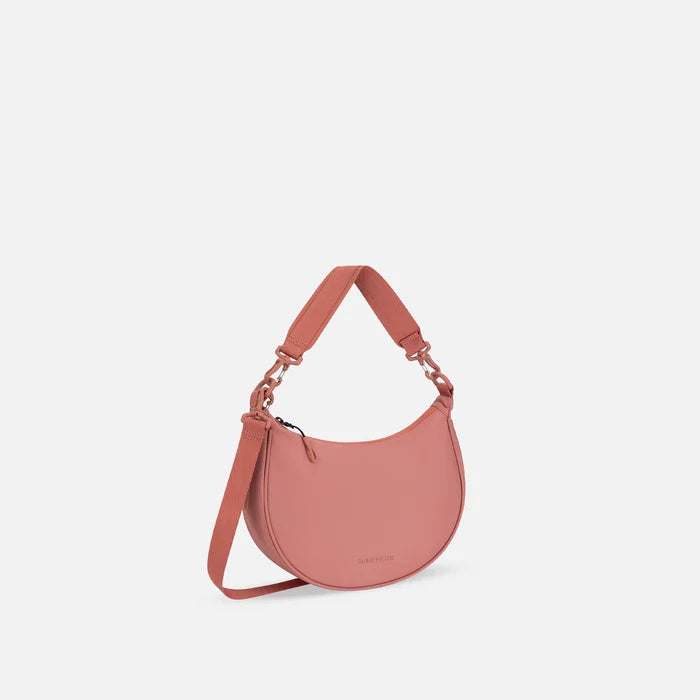 A Sherpani Mina Desert Pink Medium Crossbody Bag, 3/4 view showing strap options on white background.  #color_desert-pink
