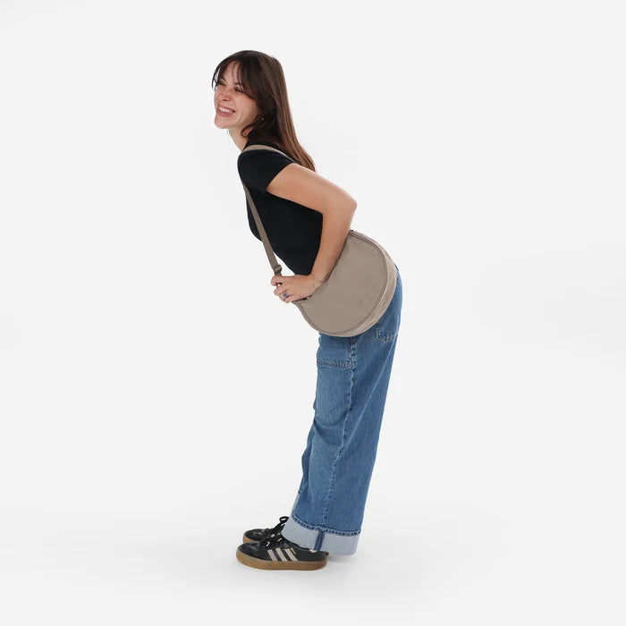 Woman wearing a Sherpani Mina Dune Tan Medium Crossbody Bag against white background. #color_dune-tan