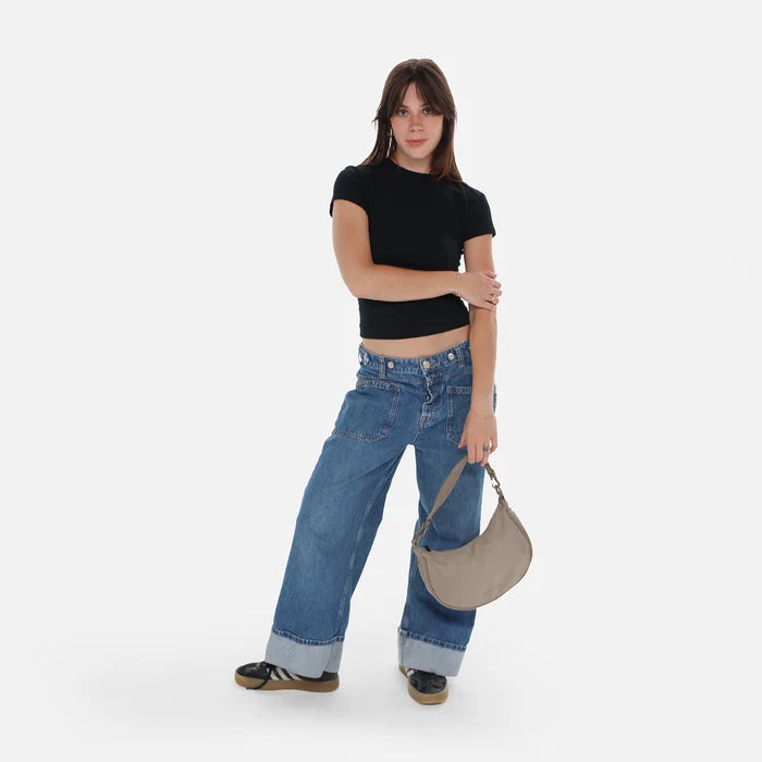 A woman holding a Sherpani Mina Dune Medium Crossbody Bag in her hands with short-strap attachment. #color_dune-tan