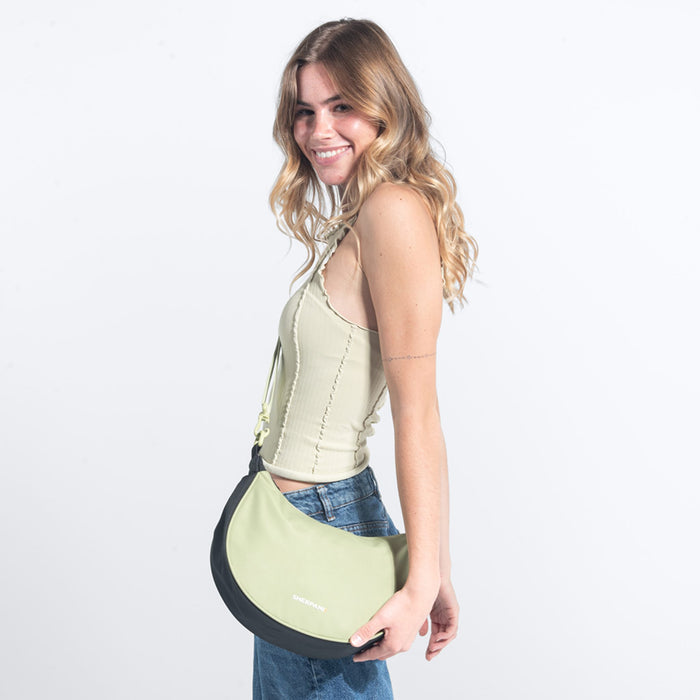Woman wearing a Sherpani Mina Palm Green Medium Crossbody Bag against white background. #color_palm-green