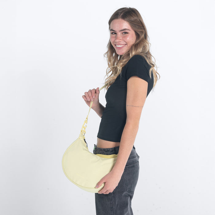 Woman wearing a Sherpani Mina Sol Yellow Medium Crossbody Bag against white background. #color_sol-yellow