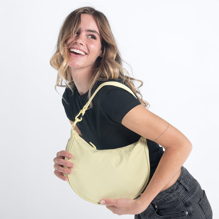 Woman wearing a Sherpani Mina Sol Yellow Medium Crossbody Bag against white background. #color_sol-yellow
