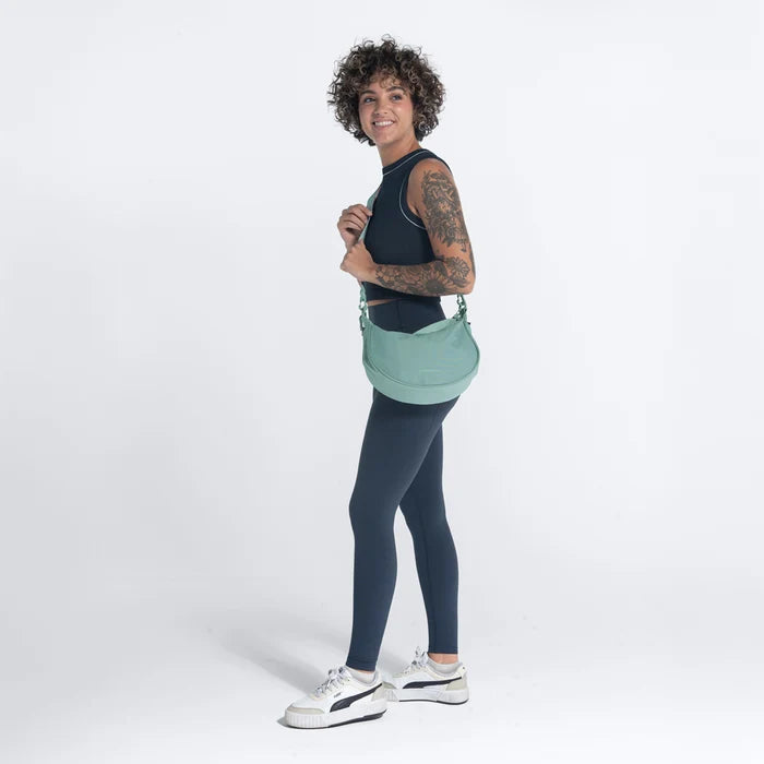 A woman wearing a Sherpani Mina Surf Blue Medium Crossbody Bag in her hands with a short-strap attachment. #color_surf-blue